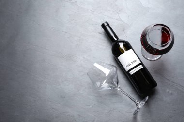 Gözlük ve şişe renkli arka plan üzerinde kırmızı şarap, düz yatıyordu. Metin için alan