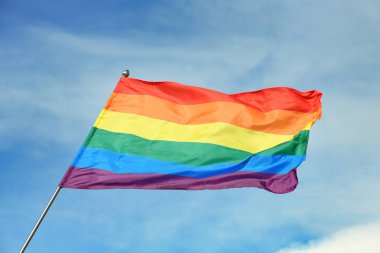 Parlak gökkuşağı gay bayrağı mavi gökyüzüne karşı çırpınan. Lgbt topluluğu