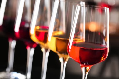 Bulanık arka planda farklı şaraplar içeren bardak sırası, yakın çekim