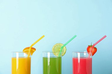 Renk arka planda farklı meyve suları ve pipetler ile üç bardak