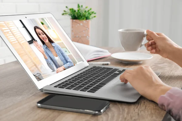 Женщина, использующая ноутбук для разговора через видео чат за столом, крупным планом — стоковое фото