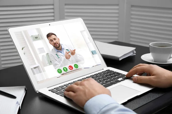 Чоловік використовує ноутбук для онлайн-консультації з лікарем через відео чат за столом, крупним планом — стокове фото