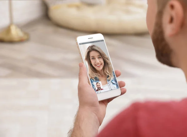 Молодой человек, использующий смартфон для разговора с подругой через видео чат дома, крупным планом — стоковое фото