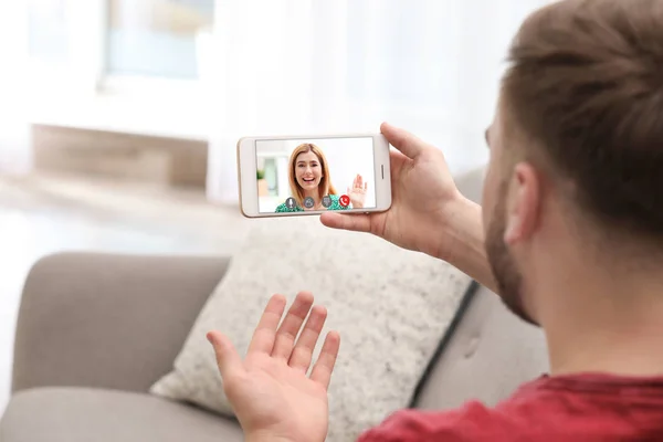Молодой человек, использующий смартфон для разговора с подругой через видео чат дома, крупным планом — стоковое фото