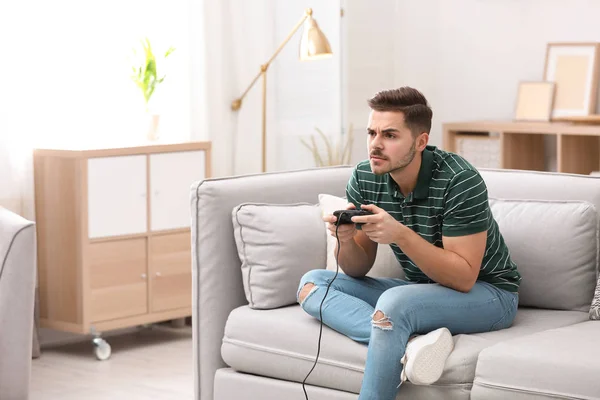 Jeune homme émotionnel jouant à des jeux vidéo à la maison — Photo