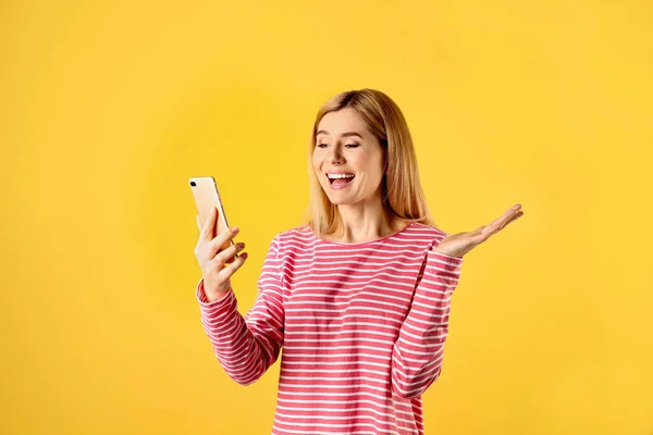 Mulher usando telefone celular para bate-papo de vídeo em fundo de cor — Fotografia de Stock