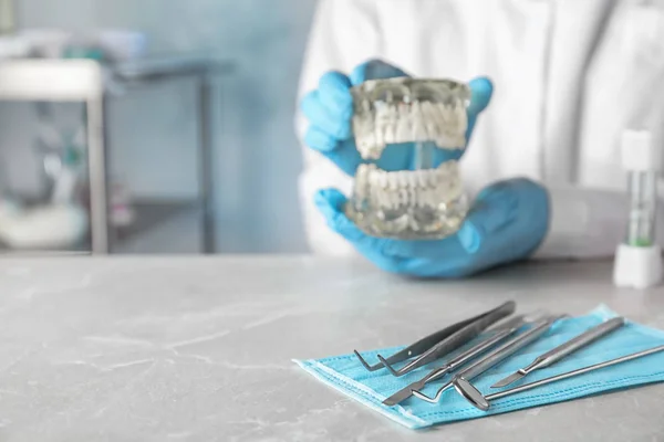 Tandarts gereedschap en wazig Doctor met typodont tanden aan tafel, close-up. Ruimte voor tekst — Stockfoto
