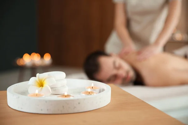 Composizione con candele e uomo sfocato che riceve massaggi nel salone spa. Spazio per testo — Foto Stock