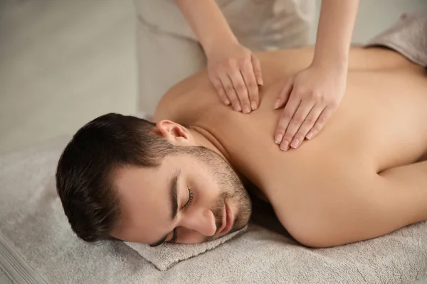 Bonito homem recebendo massagem de volta no salão de spa — Fotografia de Stock