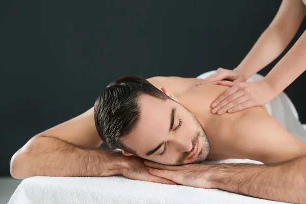 Schöner Mann, der Rückenmassage auf schwarzem Hintergrund erhält. Wellness Service — Stockfoto