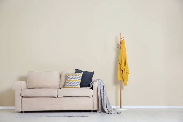 Salon intérieur minimaliste avec canapé confortable, oreillers et plaid près du mur de lumière. Espace pour le texte — Photo