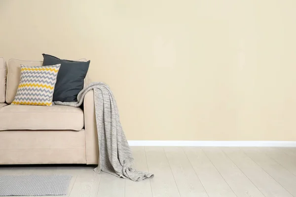 Interior minimalista de la sala de estar con sofá acogedor, almohadas y cuadros cerca de la pared de luz. Espacio para texto —  Fotos de Stock