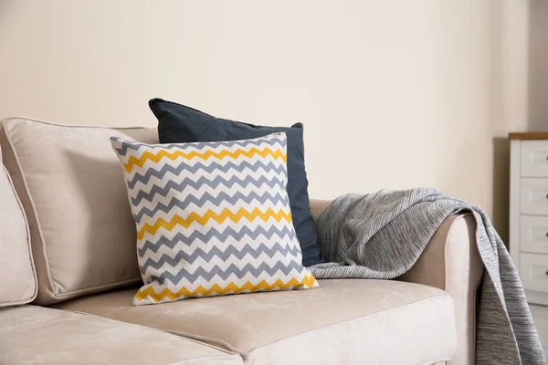 Przytulna sofa z poduszkami i kratą w pobliżu lekkiej ściany. Pomysł na pokój dzienny projektowanie wnętrz — Zdjęcie stockowe