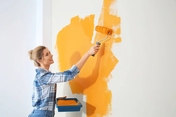 Χαρούμενη γυναίκα ζωγραφική τοίχο σε εσωτερικούς χώρους, Χώρος για το κείμενο. Επισκευή σπιτιού — Φωτογραφία Αρχείου