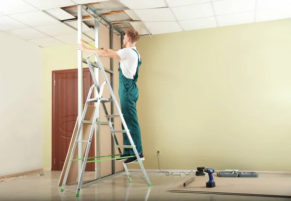 Jovem trabalhador instalando drywall dentro de casa. Serviço de reparação em casa — Fotografia de Stock