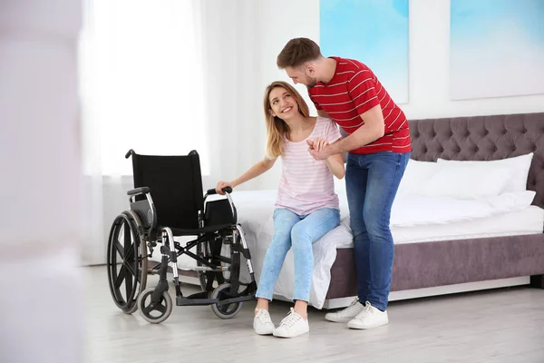 Człowiek pomaga niepełnosprawnej kobiety dostać się na wózku inwalidzkim w domu — Zdjęcie stockowe