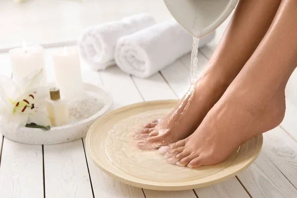 Вид крупным планом женщины, наполняющей посуду водой для ванны для ног в помещении. Лечение — стоковое фото