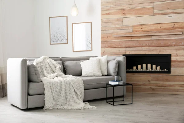 Gemütliches Sofa mit Kissen und Plaid in der Nähe dekorativen Kamin im Wohnzimmer. Innenausbau — Stockfoto