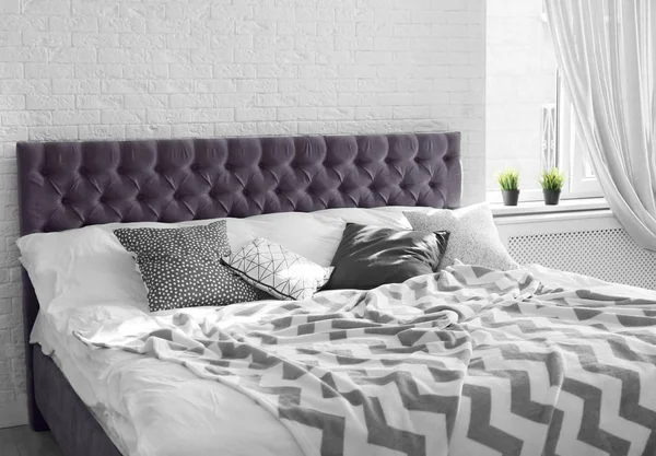 Bed with pillows and plaid near brick wall. Interior design — Stock Photo, Image