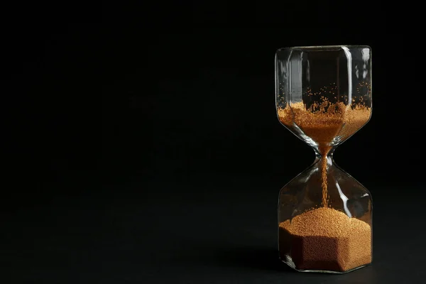Пісочний годинник із золотим піском на чорному тлі. Простір для тексту — стокове фото