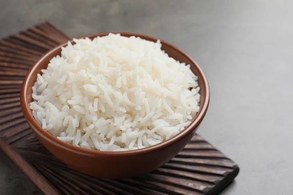 Tigela de saboroso arroz branco cozido na mesa cinza — Fotografia de Stock