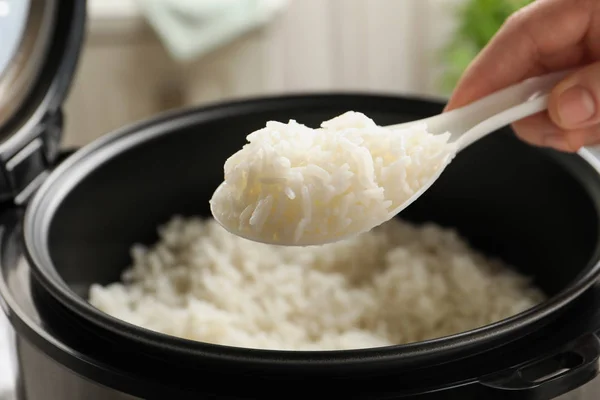 Женщина берет вкусный рис с ложкой из плиты на кухне, крупным планом — стоковое фото