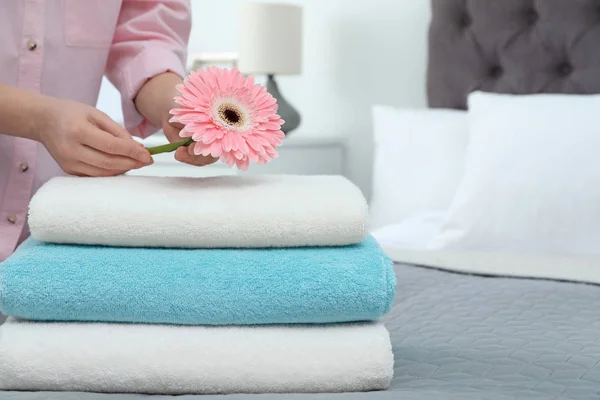 Woman putting flower on stack of clean towels in bedroom. Space for text — 스톡 사진