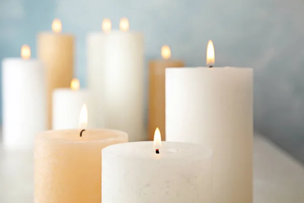 Burning candles on table against color background, closeup — Stock Photo, Image