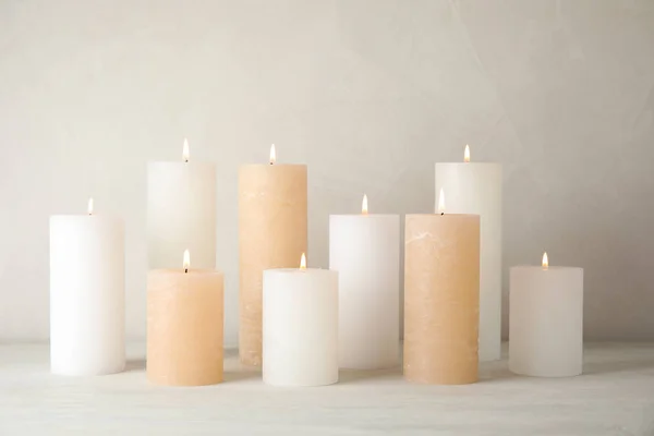 Burning candles on table against light background — Stock Photo, Image