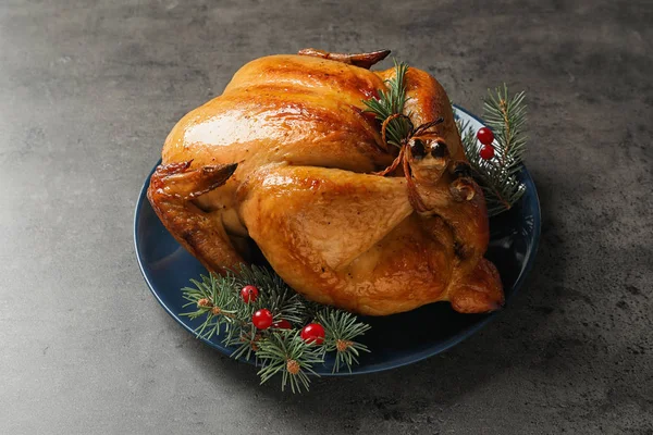 Platter of cooked turkey with cranberry and fir tree branches on grey background