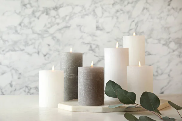 Komposition med brinnande ljus på bordet mot marmor bakgrund — Stockfoto