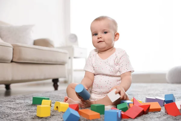 Söt baby flicka leker med byggstenar i rummet — Stockfoto