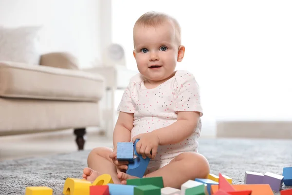Söt baby flicka leker med byggstenar i rummet — Stockfoto
