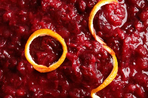 Tasty cranberry sauce with citrus zest as background, top view — Stock Photo, Image