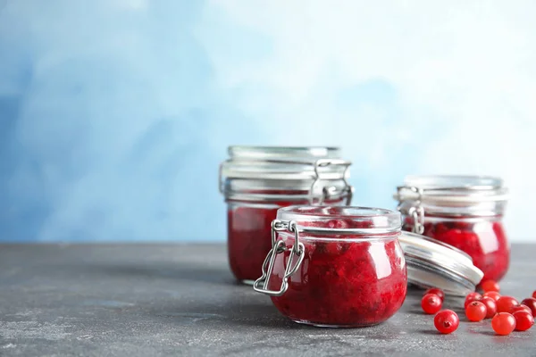 Frascos de vidro com molho de cranberry saboroso na mesa. Espaço para texto — Fotografia de Stock