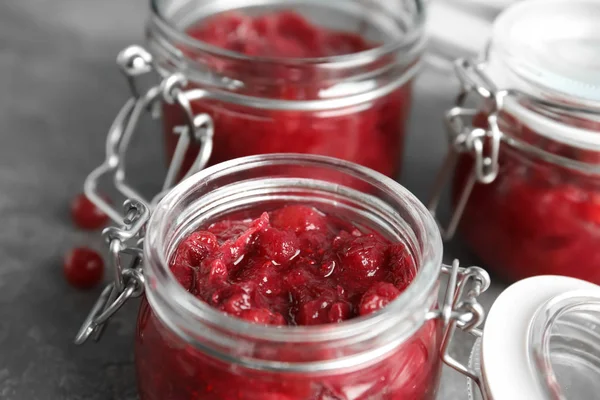Frascos de vidro com molho de cranberry saboroso na mesa, close-up — Fotografia de Stock