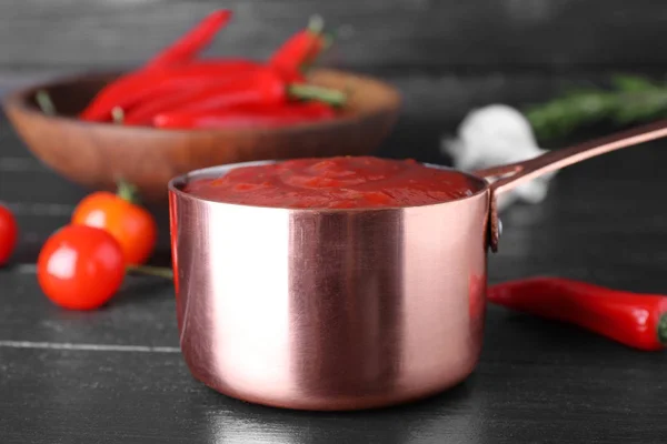 Pan of hot chili sauce and ingredients on table — Stock Photo, Image