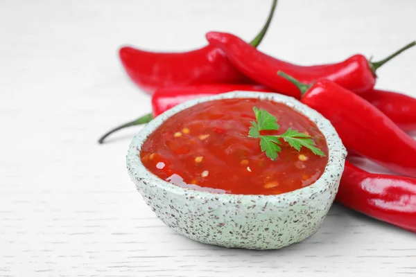 Bowl of hot chili sauce with parsley on table, closeup — Stock Photo, Image