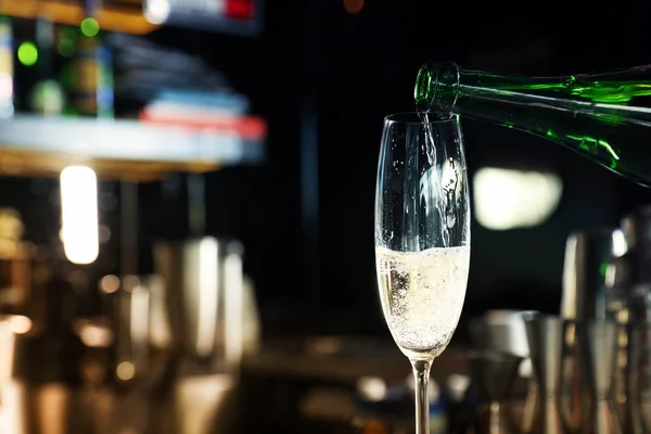 Gieten Champagne van fles in glas in bar. Ruimte voor tekst — Stockfoto