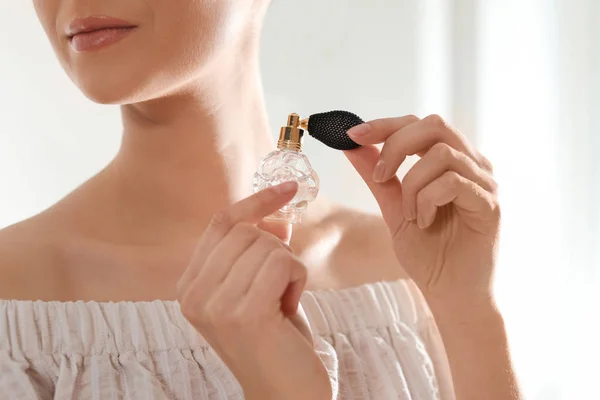 Young woman with bottle of perfume on blurred background, closeup — Stock Photo, Image