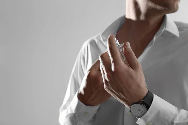 Hombre guapo aplicando perfume en el cuello sobre fondo claro, primer plano. Espacio para texto —  Fotos de Stock