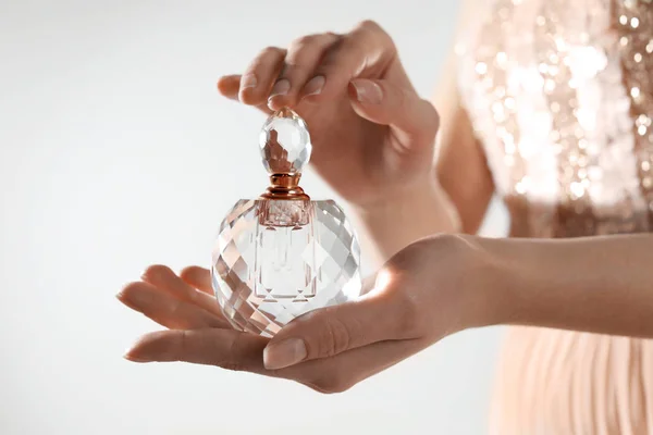 Young woman with bottle of perfume on light background, closeup — Stock Photo, Image