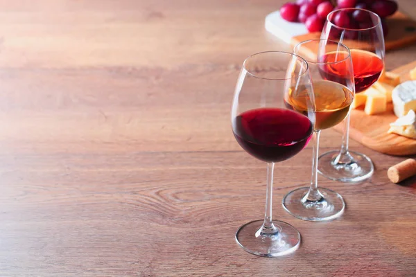 Copos com diferentes vinhos e aperitivos em mesa de madeira. Espaço para texto — Fotografia de Stock