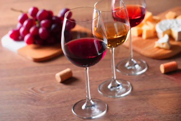 Bicchieri con diversi vini e antipasti sul tavolo di legno — Foto Stock