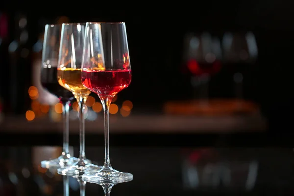 Fila de copas con diferentes vinos en barra contra fondo borroso. Espacio para texto — Foto de Stock