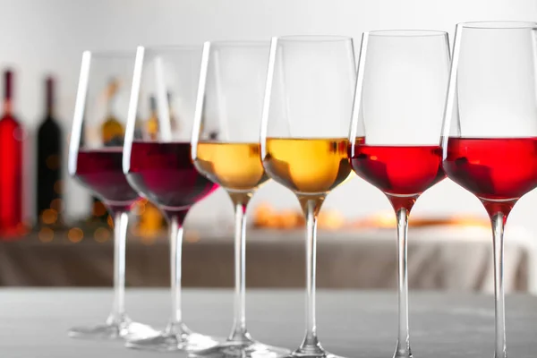 Fila de copos com diferentes vinhos na mesa contra fundo desfocado — Fotografia de Stock