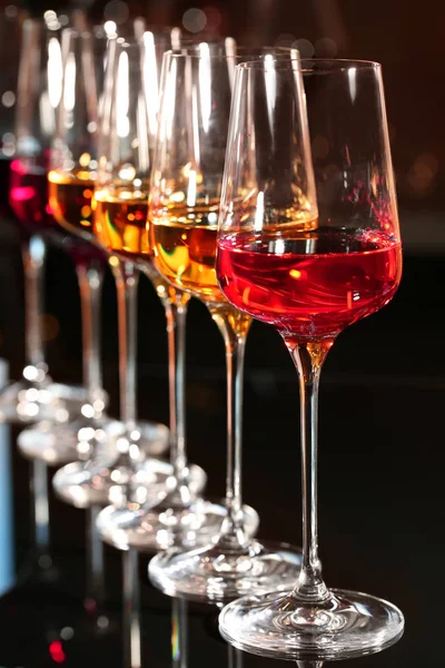 Fila di calici con diversi vini in tavola sullo sfondo sfocato — Foto Stock