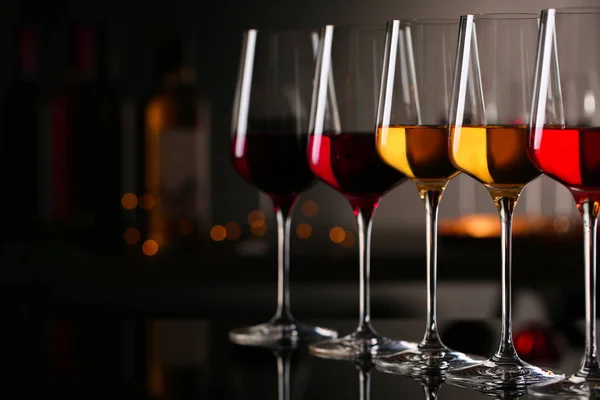 Row of glasses with different wines on bar counter against blurred background. Space for text — Stock Photo, Image