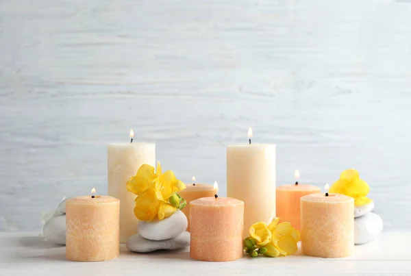 Σύνθεση από φλεγόμενα κεριά, πέτρες σπα και λουλούδια στο τραπέζι. Χώρος για κείμενο — Φωτογραφία Αρχείου