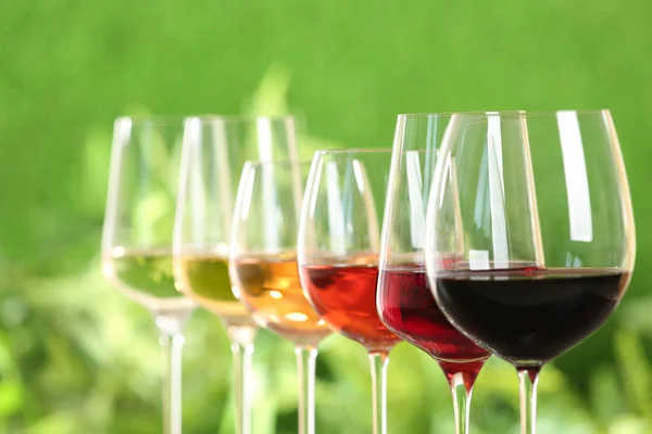 Row of glasses with different wines against blurred background, closeup — Stock Photo, Image